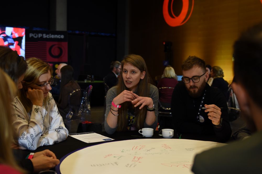 Uczestnicy konferencji w trakcie pracy, przy okrągłym stole 3 kobiety i mężczyzna w okularach